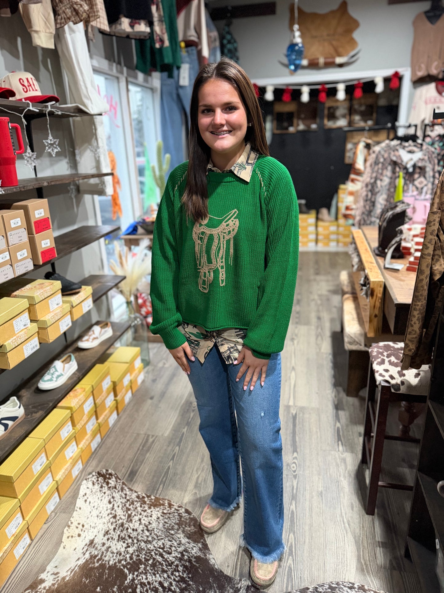 Woman wearing a green sweater with a deer design in a store setting