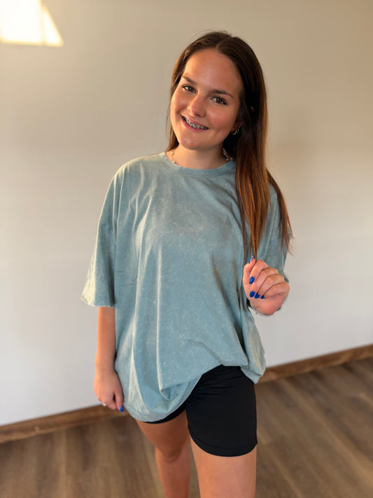 Woman wearing a light blue t-shirt and black shorts indoors.