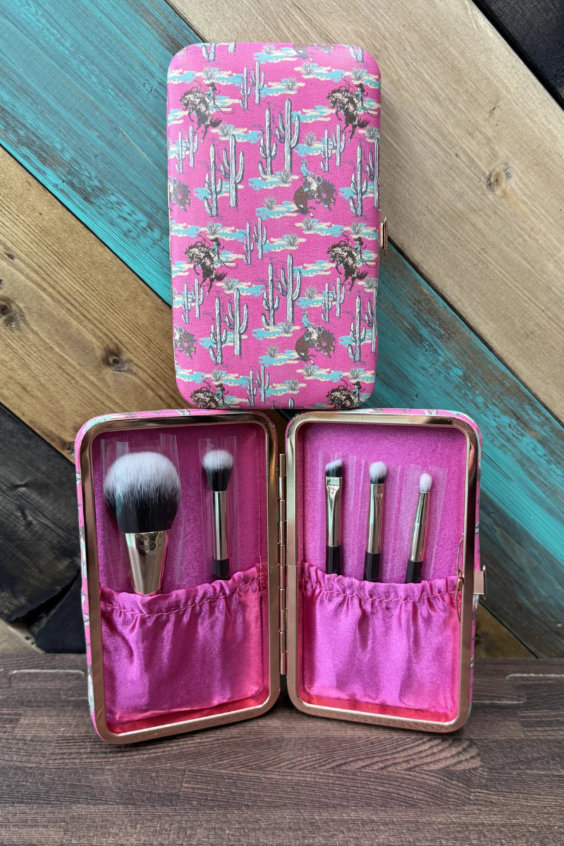 Makeup brush set in a pink case with a cactus pattern on a wooden surface.