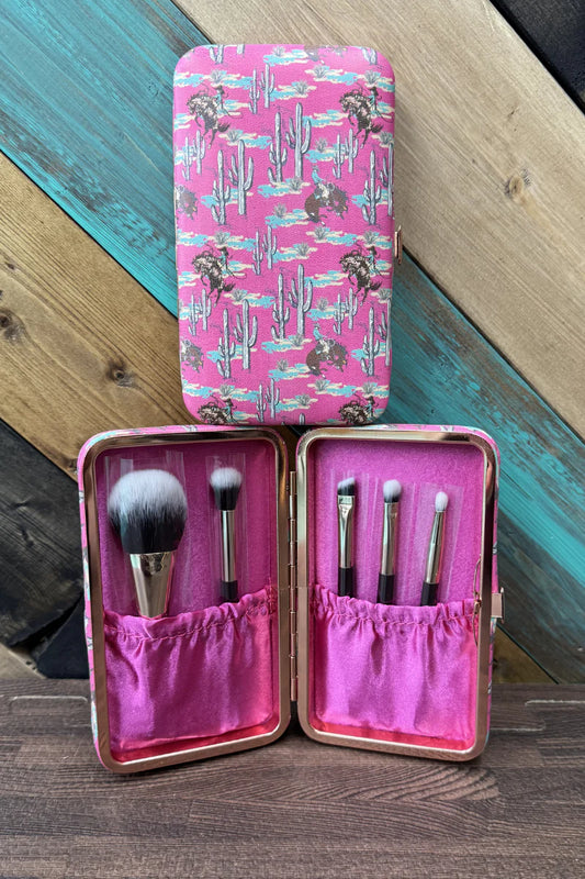 Makeup brush set in a pink case with a cactus pattern on a wooden surface.