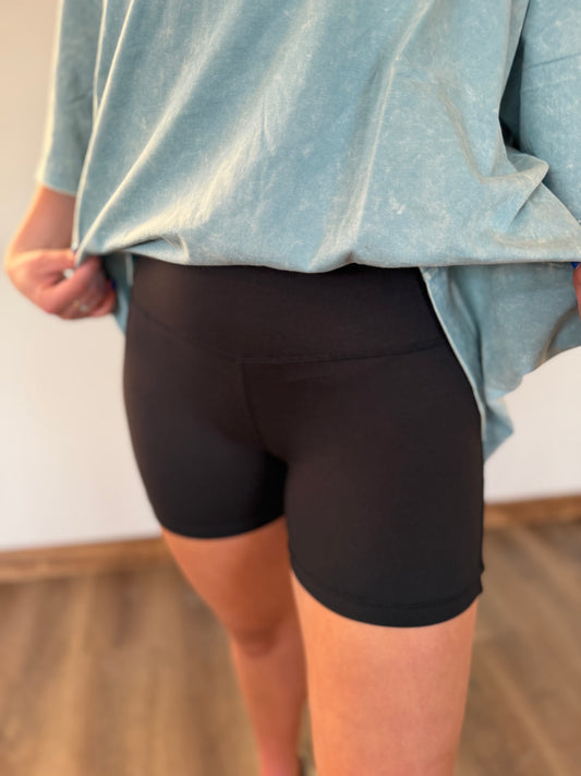 Person wearing black shorts and a light blue shirt with a blurred background