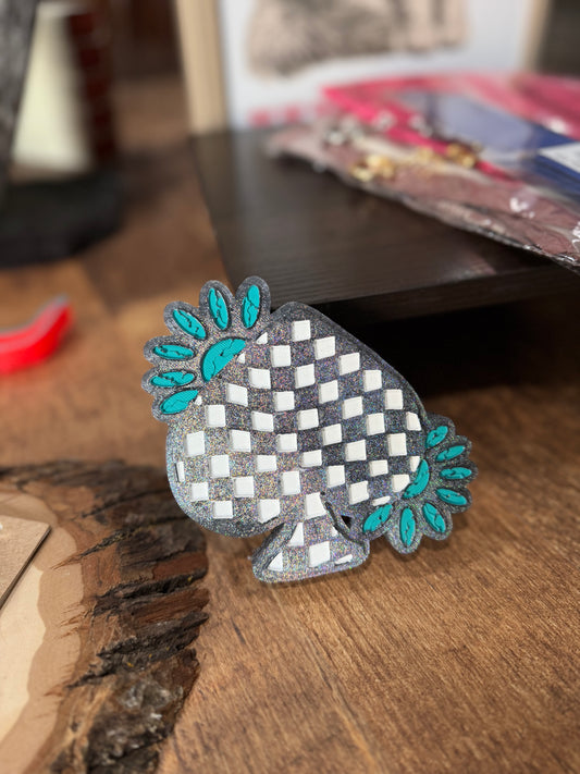 Freshie checkered object with teal accents on a wooden surface