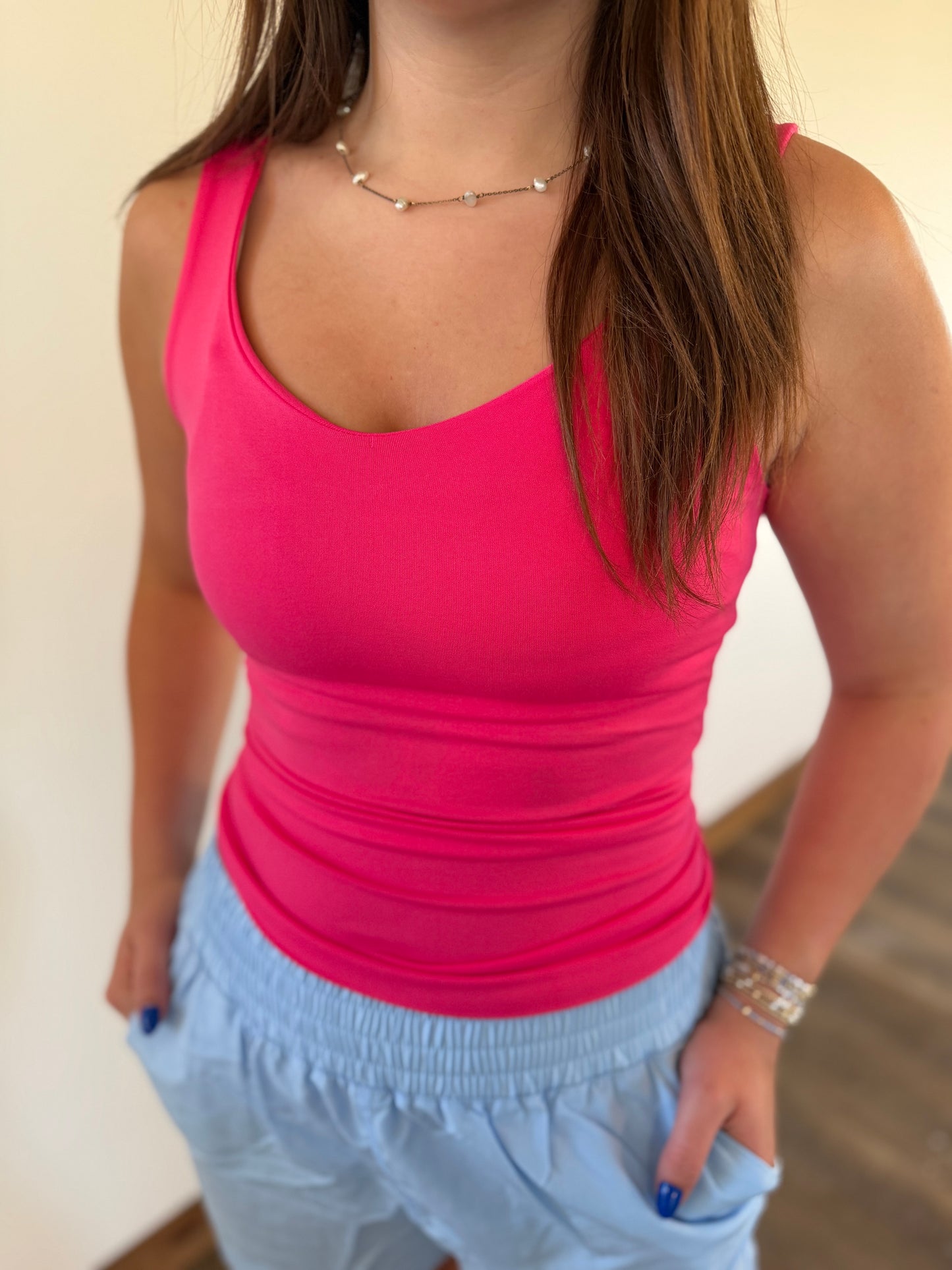 Person wearing a bright pink tank top and light blue shorts indoors.