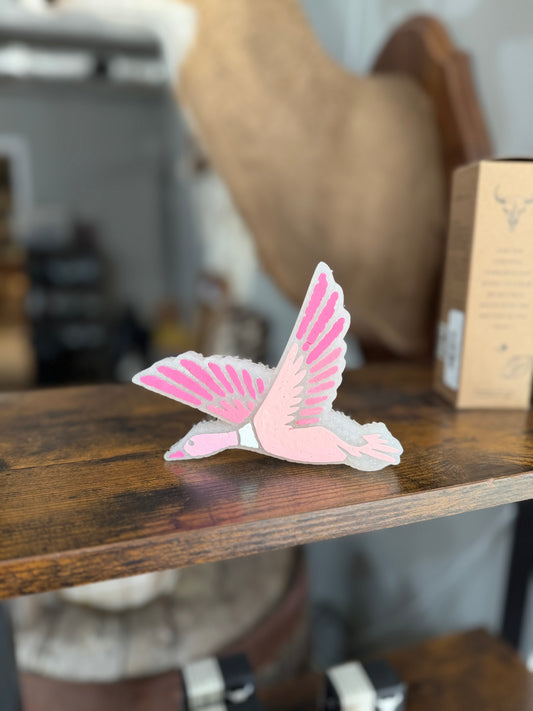Pink and white bird figurine on a wooden surface with a blurred background