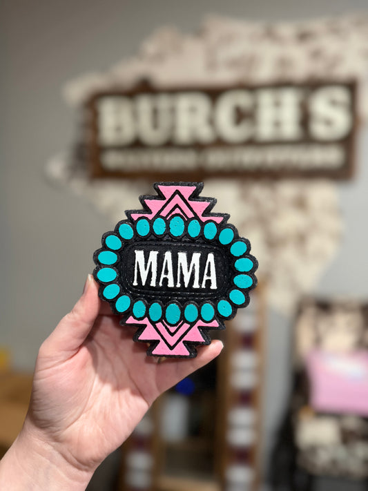 Patch with 'MAMA' text held in front of a blurred store sign.