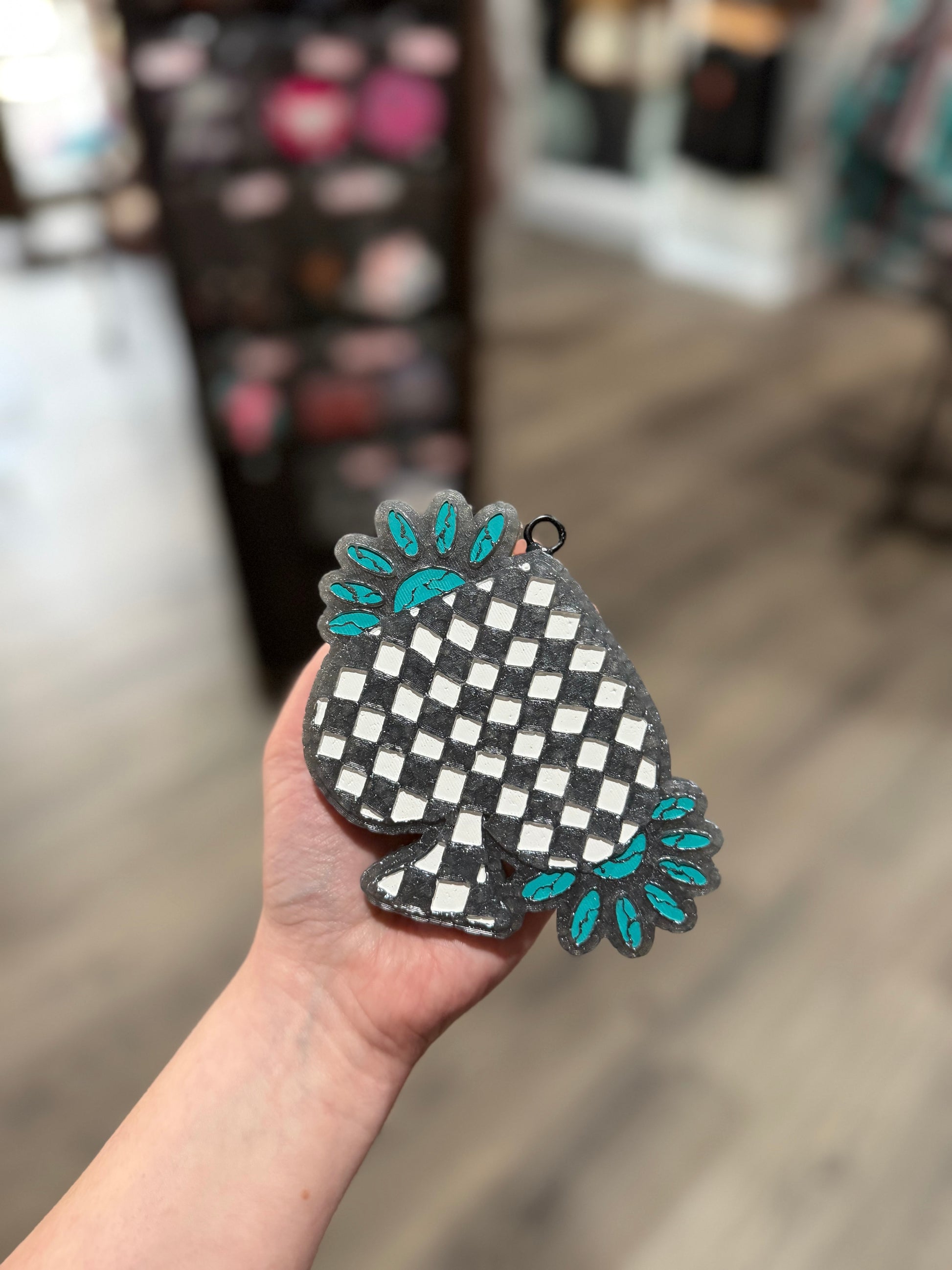 Hand holding a checkered heart-shaped object with floral designs in a store setting
