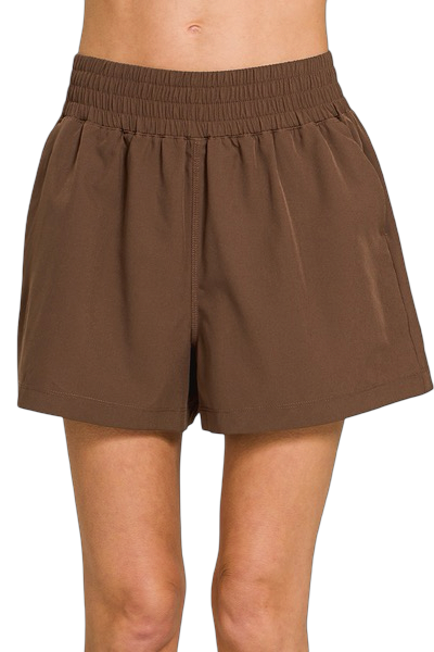 Brown shorts worn by a person on a white background