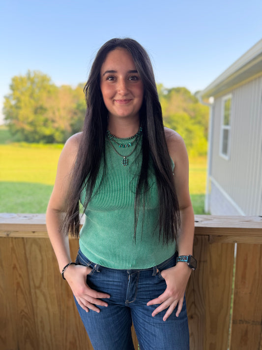 Woman standing on a deck with a scenic background of trees and open field.