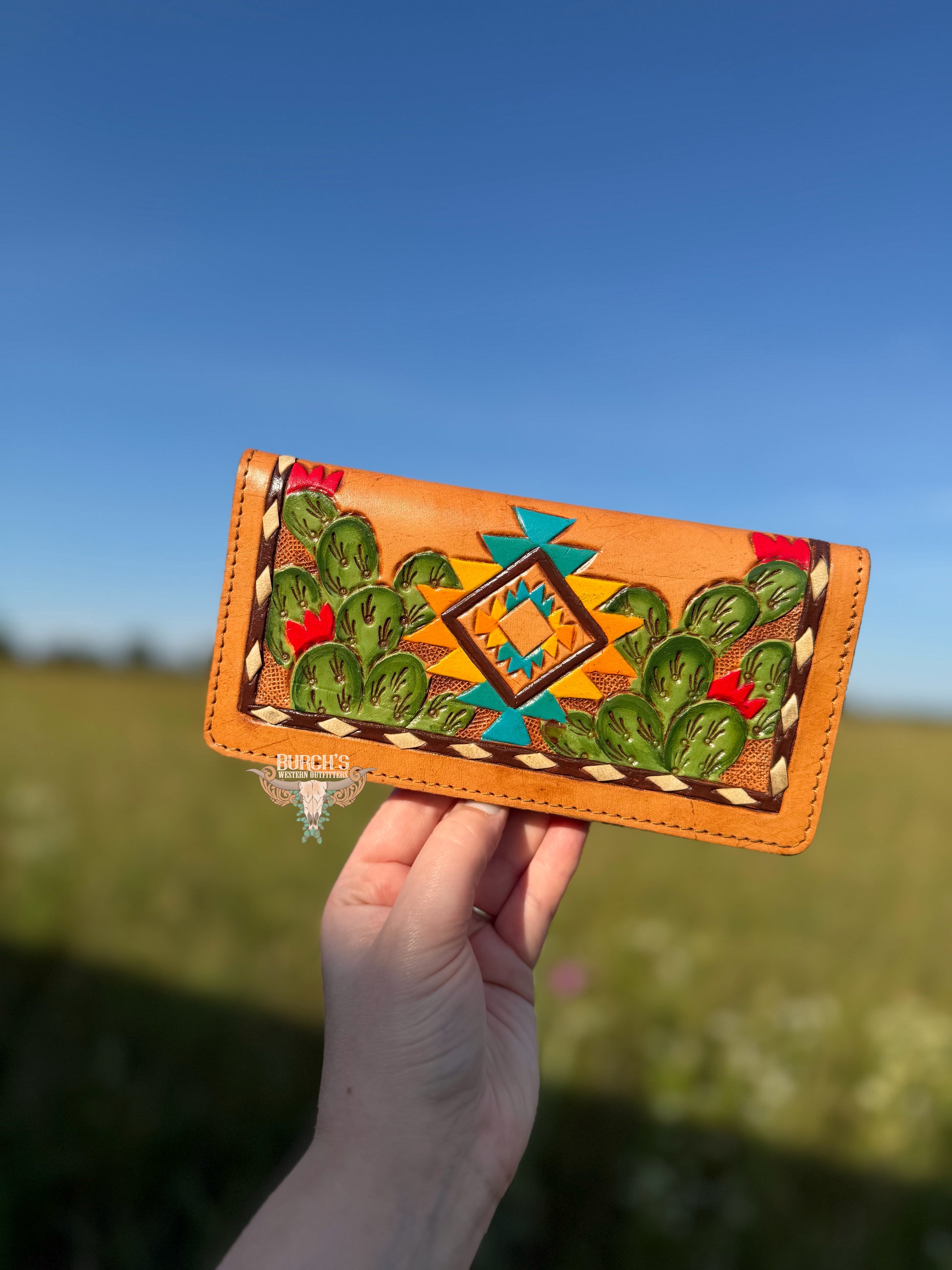 Handmade leather wallet with cactus design held against a natural background