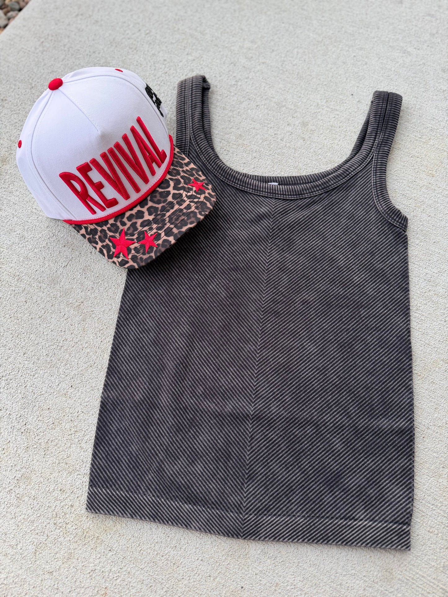 Gray tank top with a white cap and leopard print pouch on a light surface