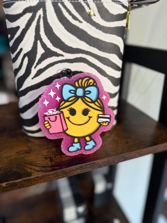 Zebra-patterned pouch with a colorful patch featuring a cartoon character holding a book on a wooden surface.