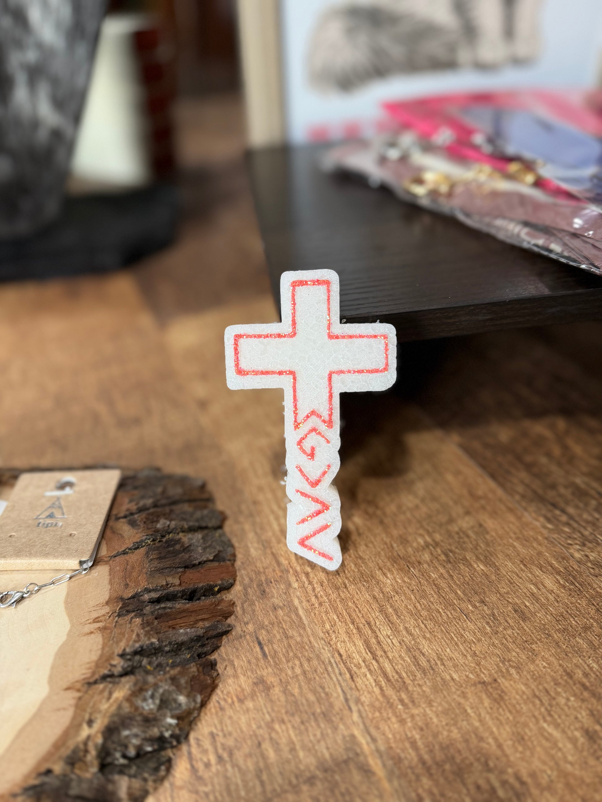Cross-shaped freshie with red accents on a wooden surface