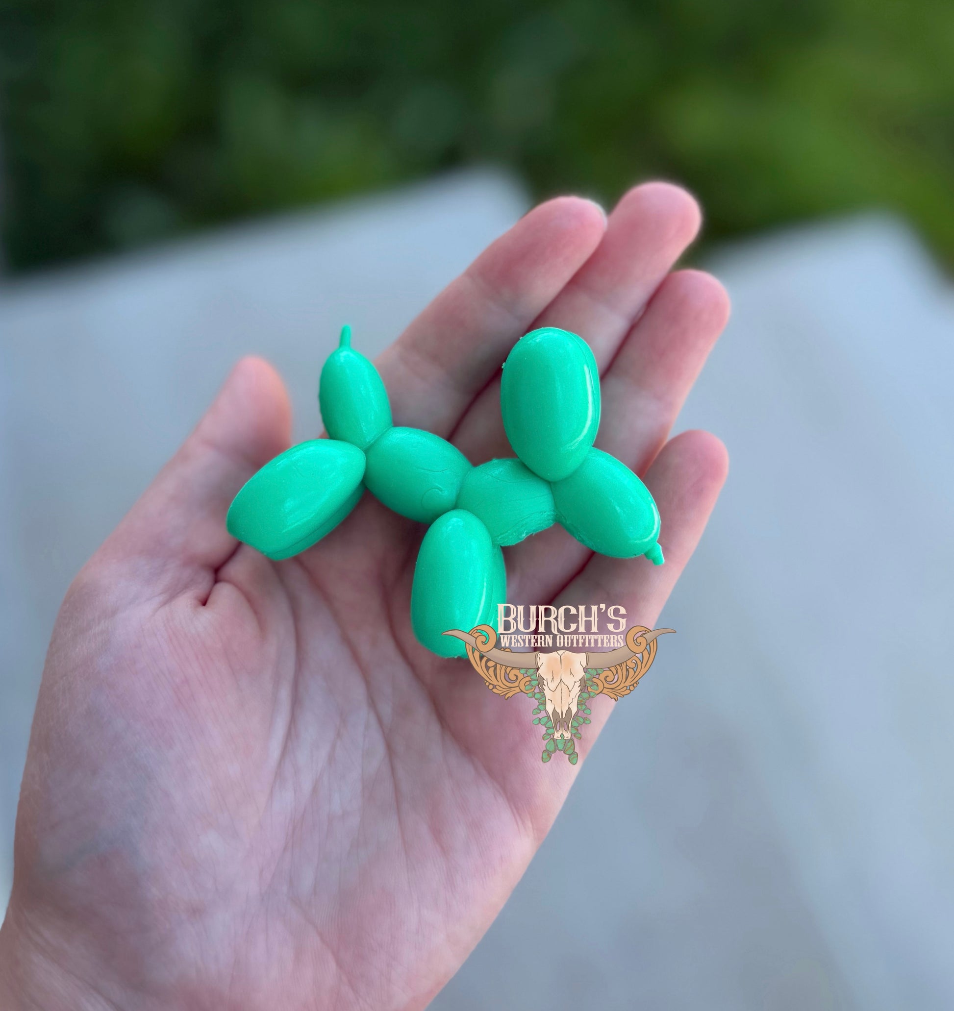Green balloon animal held in a hand with a blurred background