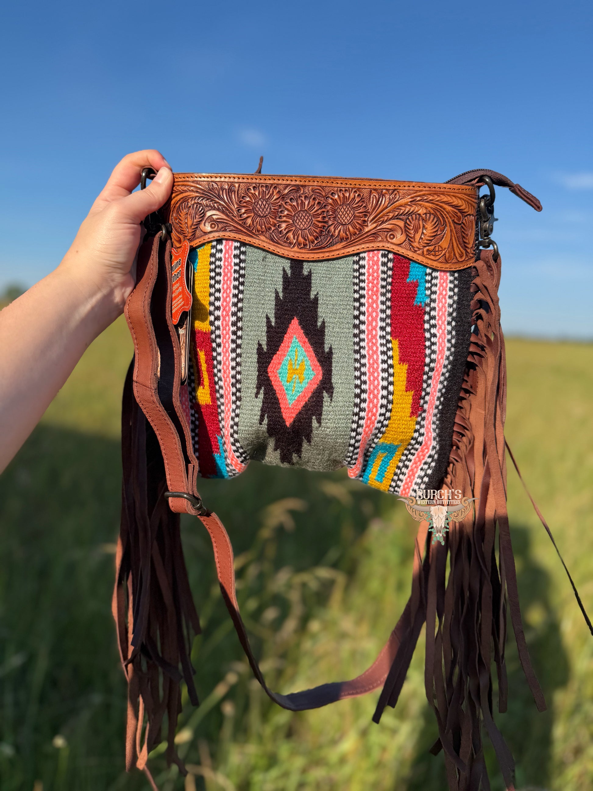 Handbag with intricate design and colorful pattern held against a natural background