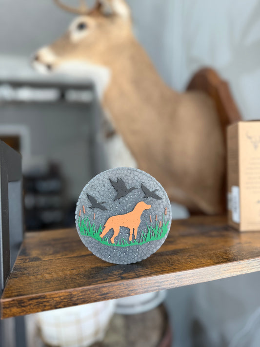 Decorative freshie with a dog and bird design on a wooden shelf.