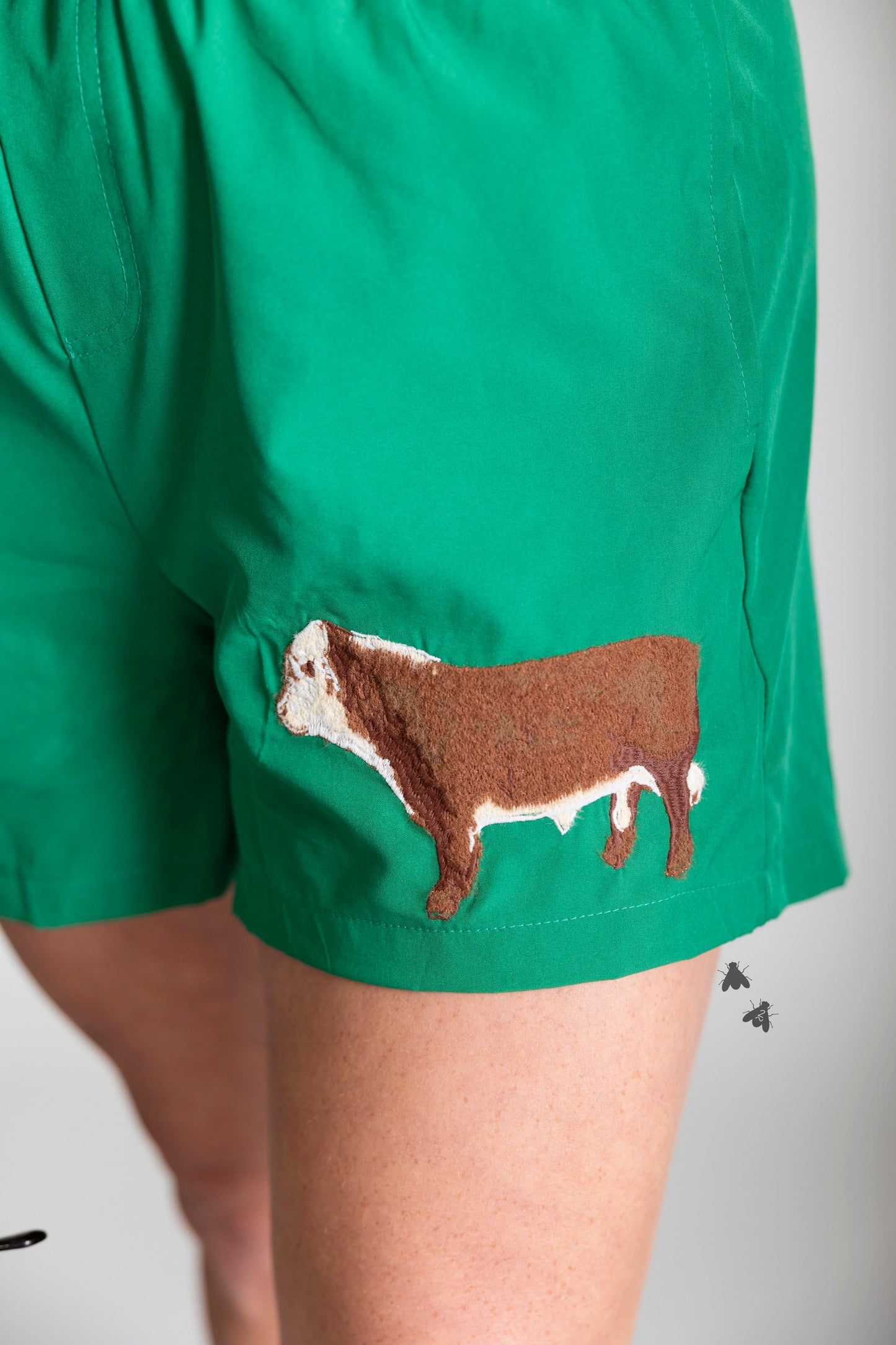 Green shorts with a brown cow patch on a plain background