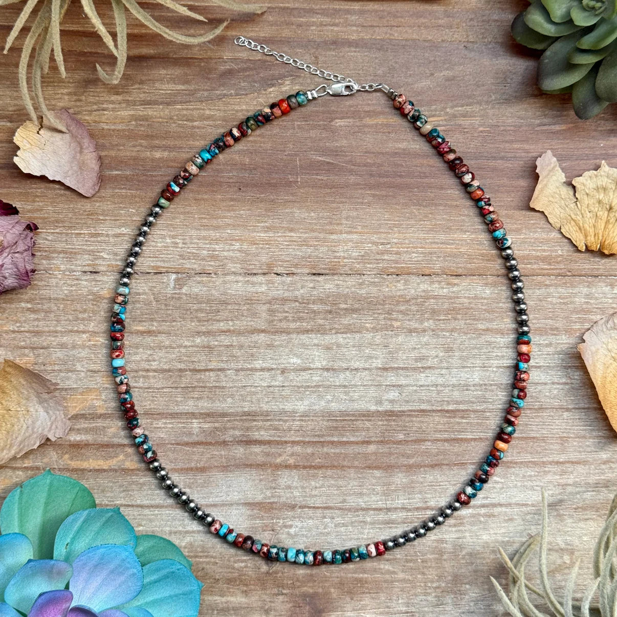 Multicolored beaded necklace on a wooden surface with decorative elements.