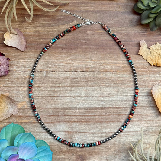 Multicolored beaded necklace on a wooden surface with decorative elements.