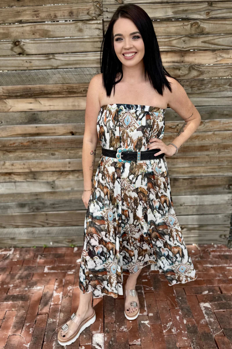 Woman wearing a patterned dress standing against a wooden wall.