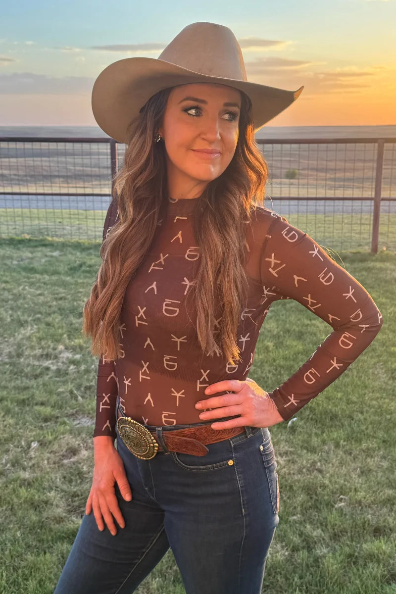 This Brown mesh top showcases an all-over pattern of classic ranch brands in a cream color, delivering Western authenticity with modern edge. The breathable mesh fabric keeps you cool while the repeating brand motif creates visual interest from every angle. Perfect for layering or wearing solo, it captures that authentic ranch aesthetic without compromising on comfort. Style it with your favorite denim or leather pieces for an effortlessly cool country vibe.

96% POLYESTER 4% SPANDEX
