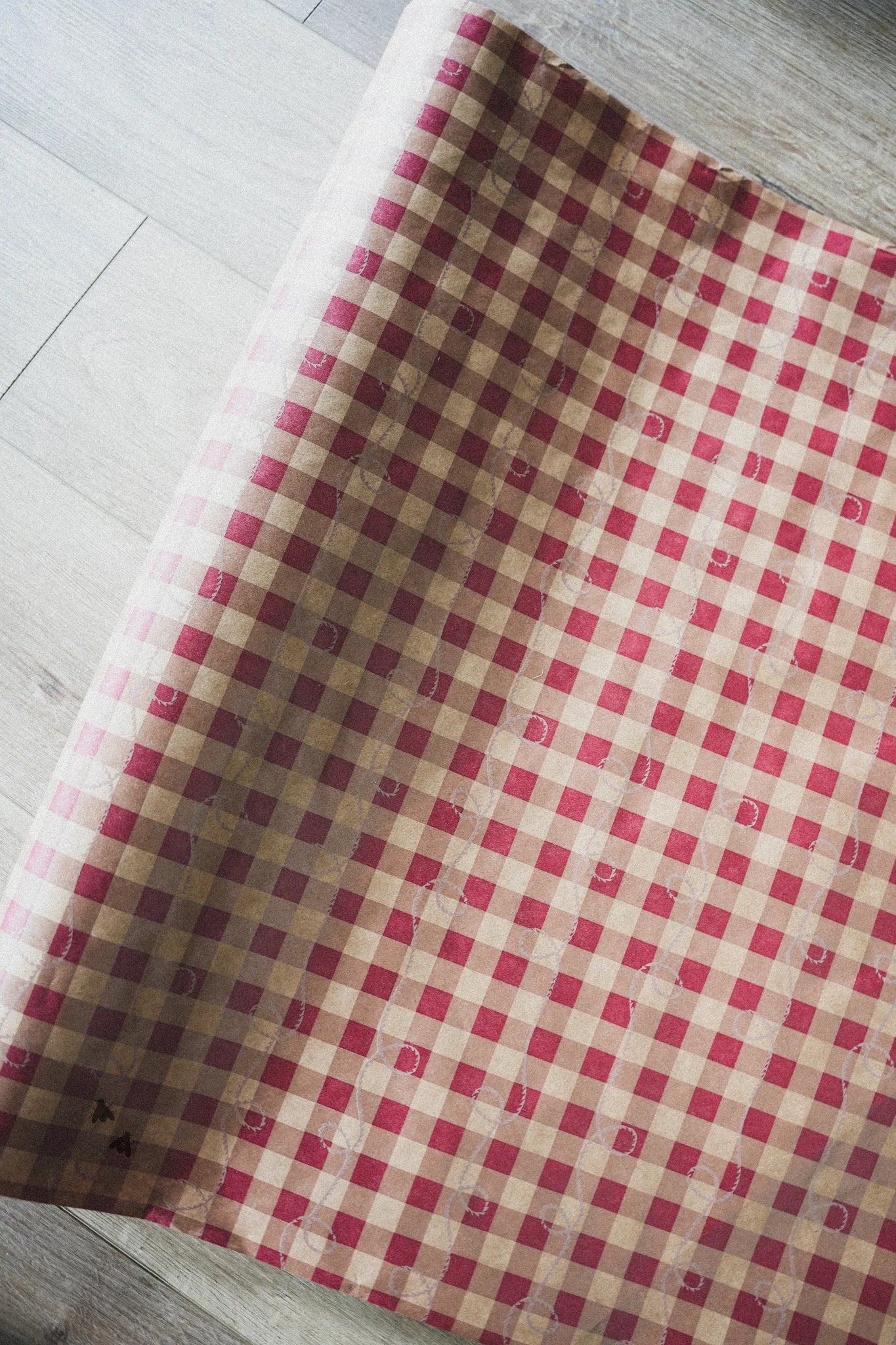 Red and beige checkered fabric on a light wooden floor